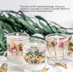 three glass jars filled with flowers on top of a white table cloth next to leaves