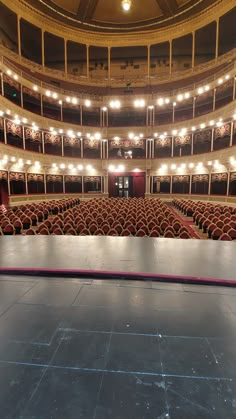 an empty auditorium with red seats and chandeliers