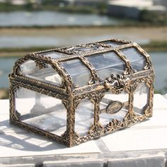 a glass and metal box sitting on top of a white brick wall with water in the background