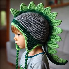 a little boy wearing a crocheted hat with green leaves on it's brim