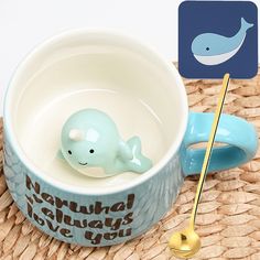 a blue whale figurine sitting in a coffee cup on a woven place mat