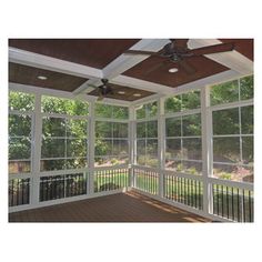 an enclosed porch with ceiling fan and windows on the side of the house that overlooks a wooded area