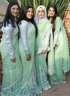 four women dressed in green and white posing for the camera with one woman wearing a headscarf