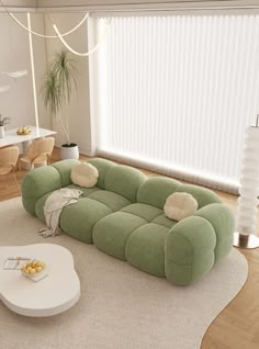 a large green couch sitting on top of a wooden floor next to a white table