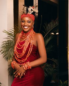 a woman in a red dress with beads on her head and necklaces around her neck