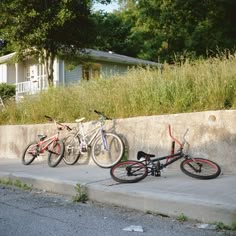 three bikes parked next to each other on the side of a road in front of a house