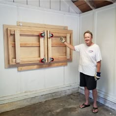 a man standing in front of a wooden cabinet with two red knobs on it