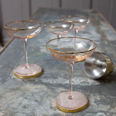 four wine glasses sitting on top of a table next to each other with gold rims