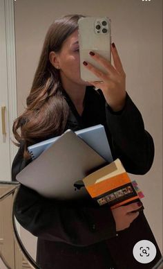 a woman taking a selfie in front of a mirror with her laptops and notebooks