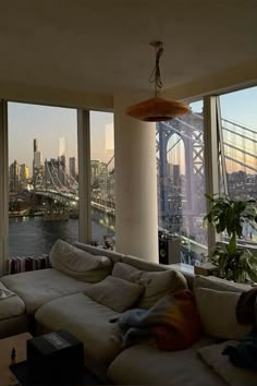 a living room filled with furniture and large windows overlooking a cityscape in the distance