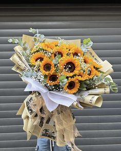 a bouquet of sunflowers is wrapped in burlock and tied with ribbon