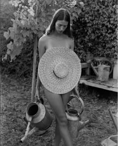 black and white photograph of a woman wearing a straw hat holding two buckets in her hand