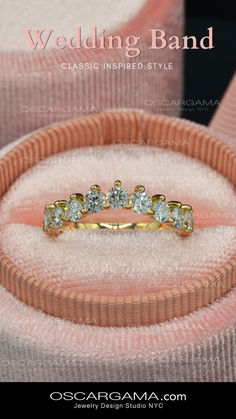 a wedding band with three stones in it on top of a pink velvet ring box