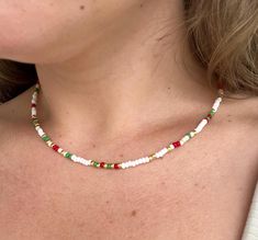 a woman wearing a red, white and green beaded necklace on her left chest