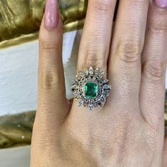 Metal: The Top Part Of The Ring Is 18kt White Gold. The Shank Is 10kt White Gold. Stones: Emerald And Diamond Shape: Round and Emerald-cut Approximate Emerald Weight: 1.50 ctw Approximate Measurements Of Emerald: 8.00 x 6.00mm Approximate Diamond Weight: .70 ctw Ring Size: 7 Sizable: No Weight of entire piece with stones: 6.10 grams Measurements Of Center Part Of Ring: 22.00mm And  Long  21.00mm wide Width Of Shoulders: 5.00mm Height Of Ring From Top To Bottom: 30.00mm Age: Vintage, approximatel Exquisite Multi-stone Platinum Jewelry, Luxury Multi-stone Emerald Jewelry, Luxury Hallmarked Emerald Ring With Diamond, Luxury Cluster Emerald Ring In Yellow Gold, Luxury Yellow Gold Cluster Emerald Ring, Luxury Silver Halo Ring With Emerald, Heirloom Emerald Ring With 17 Jewels In Platinum, Heirloom Platinum Emerald Ring With 17 Jewels, Luxury 14k Gold Emerald Ring With Halo Setting