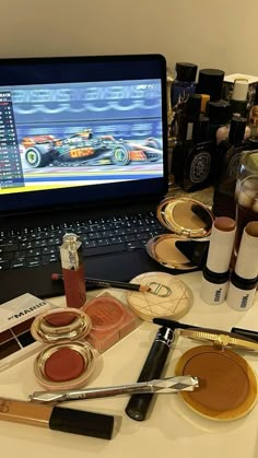 an open laptop computer sitting on top of a white desk next to makeup and cosmetics