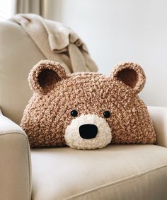 a brown teddy bear pillow sitting on top of a white chair