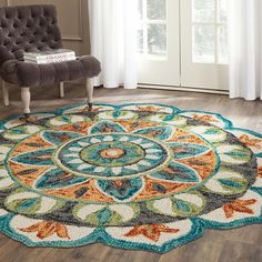 a living room area with a chair and rug on the hardwood floor, in front of a window