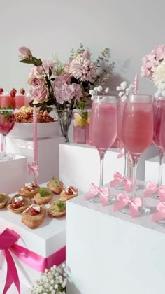 a table topped with lots of different types of desserts and drink glasses filled with pink liquid