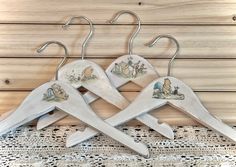 three wooden clothes hangers with winnie the pooh pictures on them, sitting on a lace doily