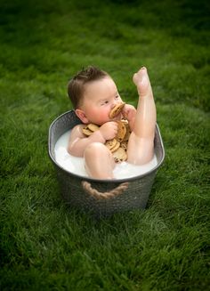 a baby sitting in a bath tub on the grass