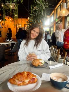 a woman sitting at a table with food in front of her and a cup of coffee