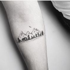 a person with a tattoo on their arm has a small group of people in the mountains