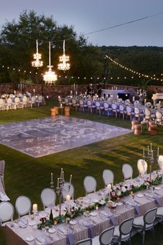 an outdoor wedding reception setup with tables and chairs set up on the lawn at dusk