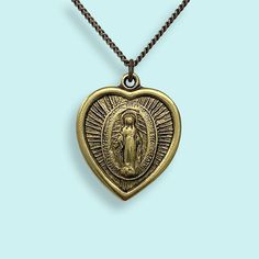 The legend of the Virgin of Guadalupe is that she first appeared to an Indigenous shepherd near Mexico City in 1531 and asked him to build a temple in her honor. Since then she’s become a beloved symbol in Mexico and beyond, representing faith, compassion and comfort to the oppressed. ⠀ Vintage Virgin of Guadalupe saint medal on aged brass curb chain. 18" chain Metal: 24kt gold plate over brass on pendant, aged brass chain Size: 1" wide pendant Lobster Clasp Nickel free Bronze Amulet Necklace For Blessing, Spiritual Necklace With Miraculous Medal For Commemoration, Gold Miraculous Medal Necklace Gift, Symbolic Miraculous Medal Jewelry As Gift, Spiritual Miraculous Medal Pendant Jewelry, Symbolic Miraculous Medal Pendant Jewelry, Miraculous Medal Medallion Necklaces For Commemoration, Miraculous Medal Medallion Necklace For Commemoration, Symbolic Bronze Locket Necklace