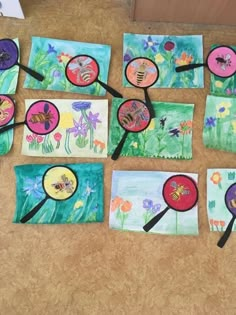 several paintings and magnifying glass on the ground with flowers in them, all painted by children