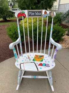 a white wooden rocking chair with writing on it and an apple themed sign that says miss weis