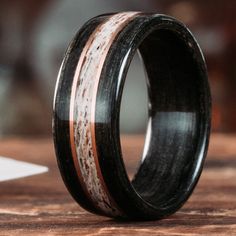 a wedding ring with wood and antler inlays sits on a wooden table