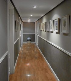 a long hallway with pictures on the wall and wood flooring in front of it