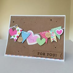 a handmade card with paper hearts and bunting flags on the string that says for you