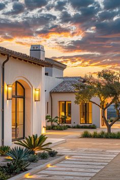 a house that is lit up at night with the sun going down in the background