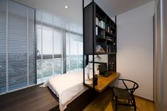 a bed sitting under a window next to a book shelf