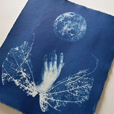 an altered photograph of a hand reaching out to the moon with leaves and branches on it