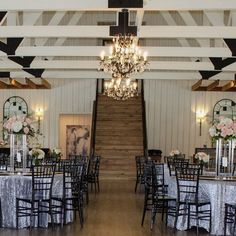 a room filled with lots of tables covered in white and black cloths next to a staircase