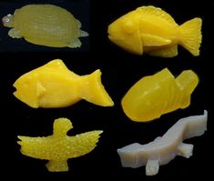 four different types of yellow plastic fish and turtle toy pieces on a black table top