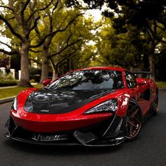 a red and black sports car parked on the side of a road next to trees