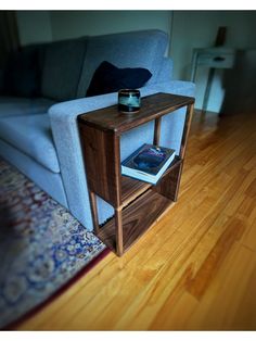 a small wooden table sitting on top of a hard wood floor next to a couch