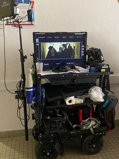 a laptop computer sitting on top of a wheel chair in front of a tv monitor