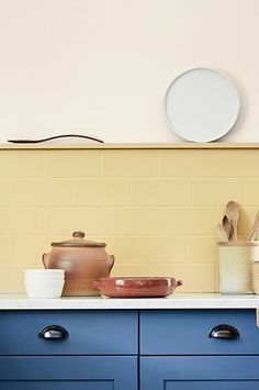 a kitchen with blue cabinets and white counter tops, including pots and pans on the stove