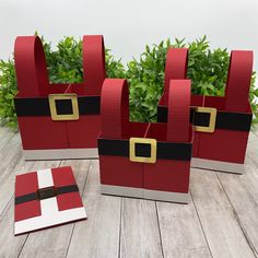 three red and white bags sitting on top of a wooden floor next to green plants