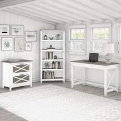 a room with white furniture and pictures on the wall, along with a computer desk