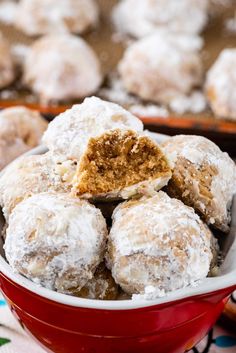 a red bowl filled with powdered sugar covered doughnuts on top of a table