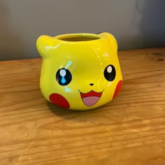 a yellow pokemon mug sitting on top of a wooden table