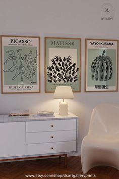 a white chair sitting next to a dresser under two posters