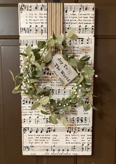 a wreath is hanging on a wall with sheet music notes and greenery around it