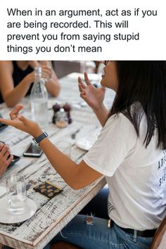 two people sitting at a table with their hands in each other's pockets and one person pointing